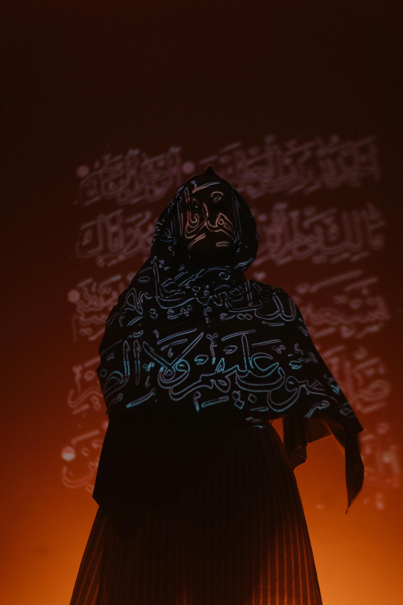 a woman in traditional attire illuminated by arabic calligraphy projections creating a mysterious aura. 4646244